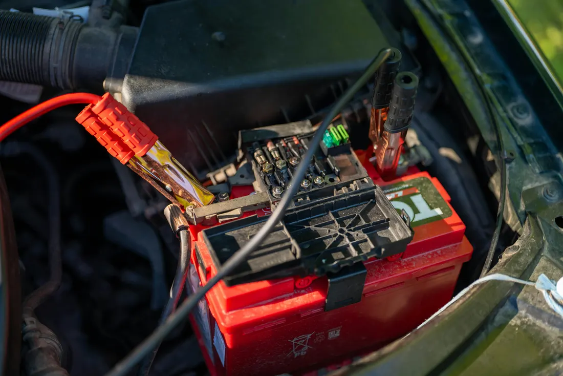 Car electrical repair — battery with jumper cables in the engine bay