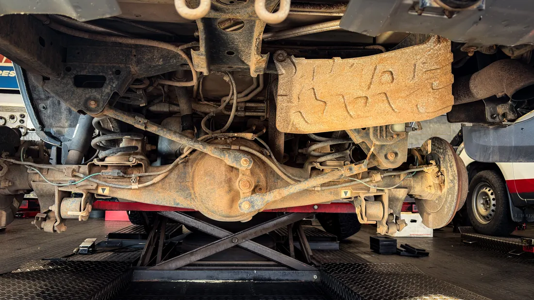 Steering & suspension repair — suspension components viewed from below on a lift